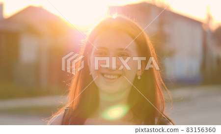 Young happy girl walks down the street smiling at sunset in the city, be satisfied with life, free woman walks in the park, walking, slow motion, student goes to study at dawn at the institute Young happy girl walks down the street smiling at sunset in the city, be satisfied with life, free woman walks in the park, walking, slow motion, student goes to study at dawn at the institute 83156360