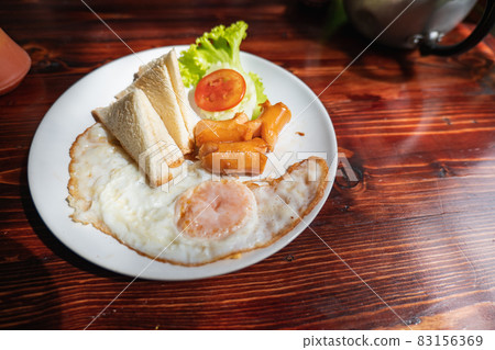 A breakfast consisting of a fried egg with a filling and a toasted bread platter of tomato and lettuce with tomato sauce is delicious. A breakfast consisting of a fried egg with a filling and a toasted bread platter of tomato and lettuce with tomato sauce is delicious. 83156369