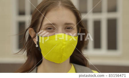 An adult schoolgirl puts on a face mask and smiles, pandemic 2022, filter air for the respiratory tract of the lungs, prevent COVID-19 infection, protect a person from coronavirus with a mask mode 83156471
