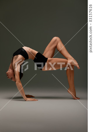 beautiful woman ballet dancer in black swimsuit posing on light grey studio background. Animal instinct 83157616