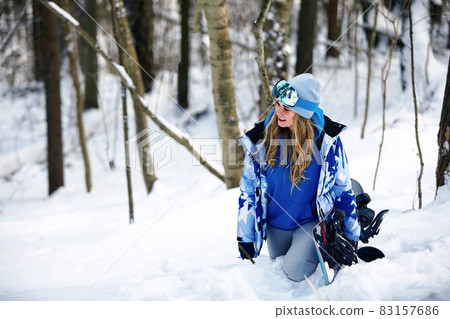 Image with a portrait of a female snowboarder wearing a helmet with a bright reflection in the glasses. On the background of high snow mountain Image with a portrait of a female snowboarder wearing a helmet with a bright reflection in the glasses. On the background of high snow mountain 83157686
