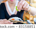 Close up on hand of a woman squeezing a lemon into a large oyster 83158851
