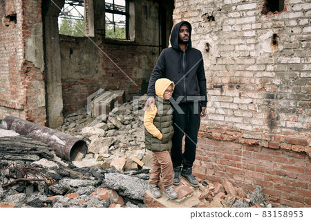 Young man and little girl standing by ruined building 83158953