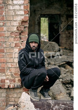 Young lonely man in casualwear sitting in ruins 83158958