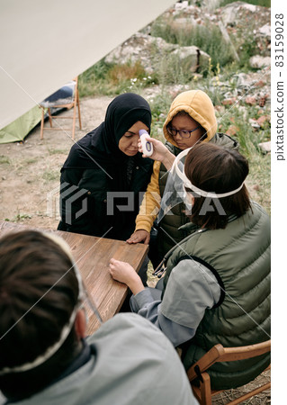 Volunteering doctor measuring body temperature of young female refugee 83159028