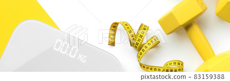 Flat lay top view scales, dumbbell and tape measure on white yellow background Flat lay top view scales, dumbbell and tape measure on white yellow background 83159388