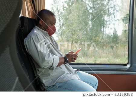 Young contemporary man in protective mask scrolling in mobile phone Young contemporary man in protective mask scrolling in mobile phone 83159398