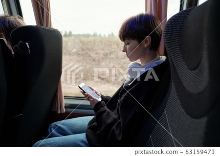 Side view of girl with smartphone sitting by window in the bus 83159471