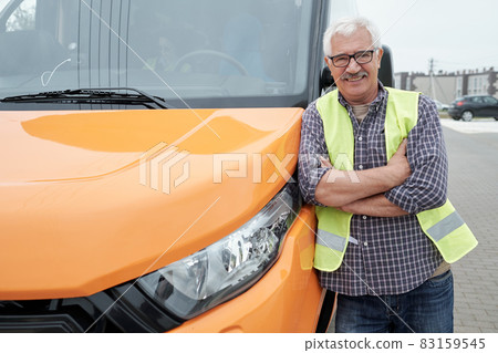 Happy mature bus driver standing by transport in the street 83159545