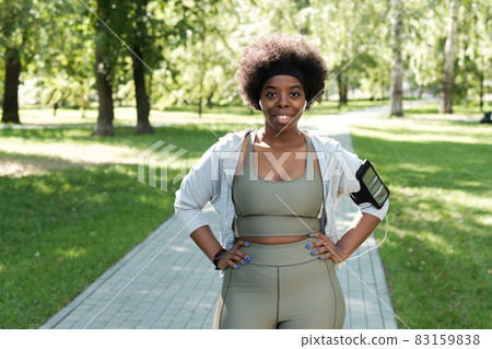Happy plus size sportswoman standing in park Happy plus size sportswoman standing in park 83159838
