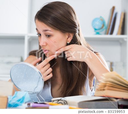 Teenager is squeezing out a pimple before makeup making Teenager is squeezing out a pimple before makeup making 83159953