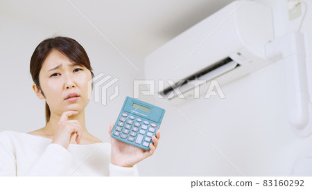 A woman thinking about the electricity bill of an air conditioner .. 83160292