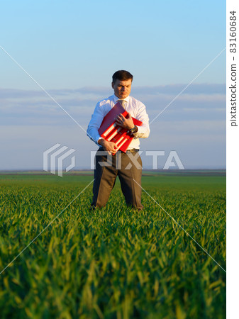 businessman holds an office red folder with documents in a green grass field - business concept businessman holds an office red folder with documents in a green grass field - business concept 83160684