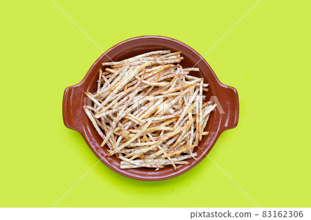 Fried taro sticks in bowl on green background. 83162306
