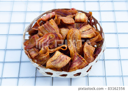 Banana slice chips in bamboo basket on white background. 83162356