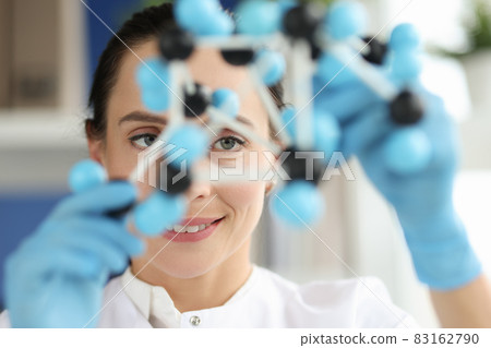 Woman scientist looks at dna layout closeup 83162790