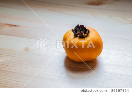 Persimmon on a wooden desk Persimmon on a wooden desk 83167564