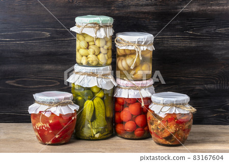 Homemade pickled cherry tomatoes, cucumbers, champignons, garlic, eggplant, red peppers in jars on wooden shelf Homemade canned and fermented foods concept Seasonal product Homemade pickled cherry tomatoes, cucumbers, champignons, garlic, eggplant, red peppers in jars on wooden shelf Homemade canned and fermented foods concept Seasonal product 83167604