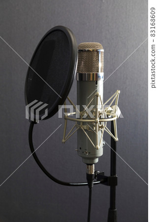 Studio microphone and pop shield on mic stand against gray background 83168609