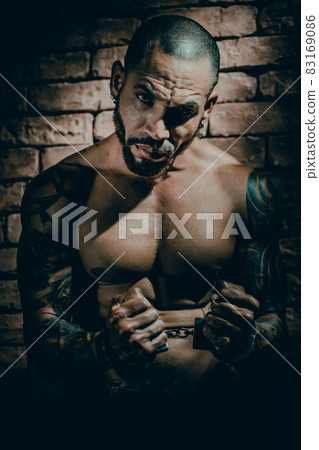 A bandit or rapist in tattoos is imprisoned in solitary confinement. Hands in handcuffs. A dangerous A bandit or rapist in tattoos is imprisoned in solitary confinement. Hands in handcuffs. A dangerous 83169086