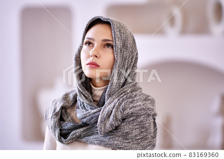 Headscarf on head of muslim woman who stands indoors. Headscarf on head of muslim woman who stands indoors. 83169360