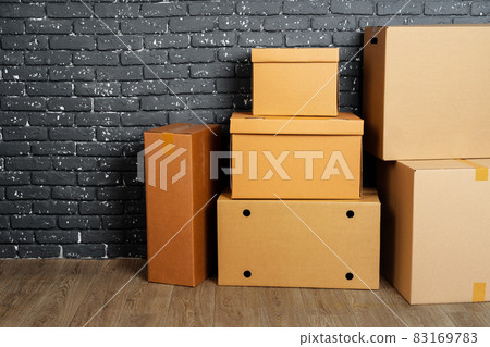 Stack of cardboard boxes in the empty room against black brick wall 83169783