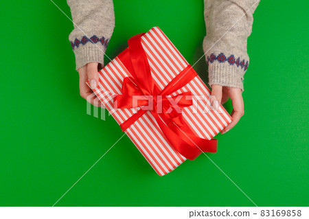 Woman hands holding gift box on green background Woman hands holding gift box on green background 83169858