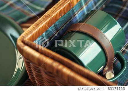 Wooden basket for picnic with plates, cups and silverware close up Wooden basket for picnic with plates, cups and silverware close up 83171133