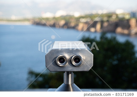 coin operated binoculars in front of mountains and sea 83171169