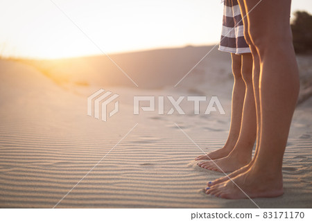 woman and her child standing on sand dunes at sunrise 83171170