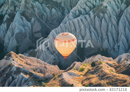 hot air balloon rising over the Cappadocian valley with chimney houses in the background hot air balloon rising over the Cappadocian valley with chimney houses in the background 83171218