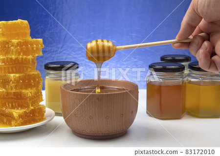 fresh honey dripping from a spoon into a plate on a blue background. organic vitamin health food 83172010