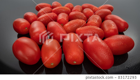 Plum tomatoes and cherry tomato composition on a dark glass background. Vegan food 83172293