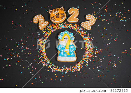 Christmas background with gingerbread on dark surface. Holiday mood card. Top view, copy space. Family traditions, DIY, celebration concept. Festive background with homemade gingerbread cookies. 83172515