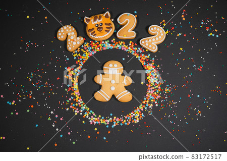 Christmas background with gingerbread on dark surface. Holiday mood card. Top view, copy space. Family traditions, DIY, celebration concept. Festive background with homemade gingerbread cookies. 83172517