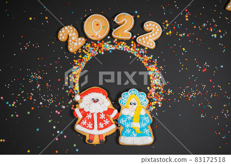Christmas background with gingerbread on dark surface. Holiday mood card. Top view, copy space. Family traditions, DIY, celebration concept. Festive background with homemade gingerbread cookies. 83172518
