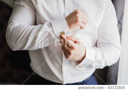 Grooms morning preparation. Handsome man getting dressed and preparing for the wedding 83172805
