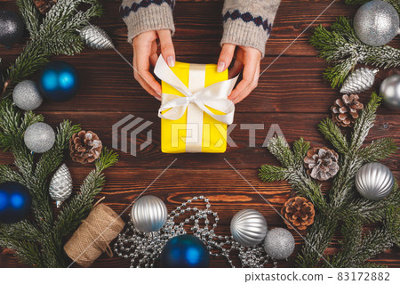 View from above of woman wearing sweater and holding a decorated present 83172882