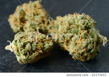 Dried cannabis blooms, macro view, close-up. Medicinal marijuana flowering with trichomes on black background 83173031