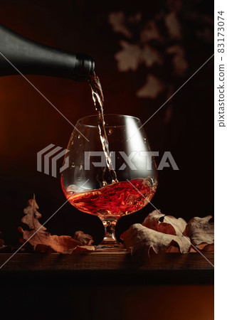 Brandy is poured from a bottle into a glass. 83173074