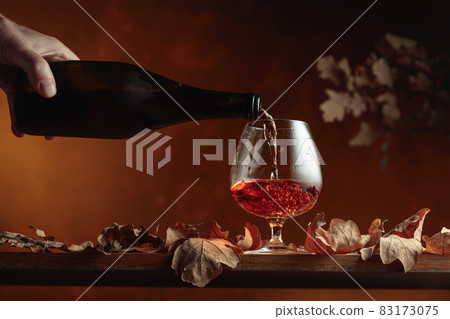 Brandy is poured from a bottle into a glass. Brandy is poured from a bottle into a glass. 83173075