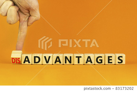 Advantages or disadvantages symbol. Businessman turns a wooden cube, changes the word Disadvantages to Advantages. Beautiful orange background, copy space. Business, advantages disadvantages concept. 83173202