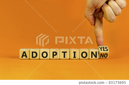 Adoption symbol. Businessman turns a wooden cube and change words 'adoption no' to 'adoption yes'. Beautiful orange background. Business and adoption concept, copy space. Adoption symbol. Businessman turns a wooden cube and change words 'adoption no' to 'adoption yes'. Beautiful orange background. Business and adoption concept, copy space. 83173605