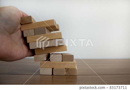 Male hand holds the model of business, made from wood blocks. Alternative risk concept, business plan and business strategy. Insurance concept. White background, copy space. 83173711