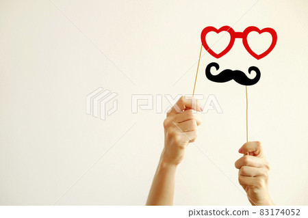 Paper party attributes in form of moustache on wooden stick. Carnival accessory concept. Paper party attributes in form of moustache on wooden stick. Carnival accessory concept. 83174052