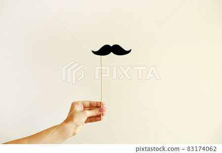 Paper party attributes in form of moustache on wooden stick. Carnival accessory concept. Paper party attributes in form of moustache on wooden stick. Carnival accessory concept. 83174062