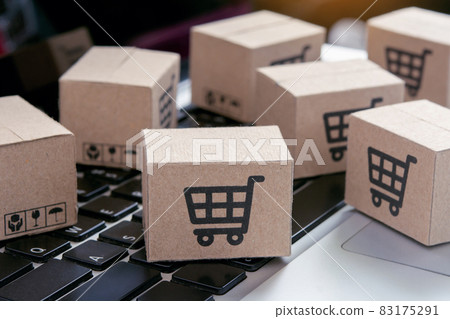 Online shopping - Paper cartons or parcel with a shopping cart logo on a laptop keyboard. Shopping service on The online web and offers home delivery.. Online shopping - Paper cartons or parcel with a shopping cart logo on a laptop keyboard. Shopping service on The online web and offers home delivery.. 83175291