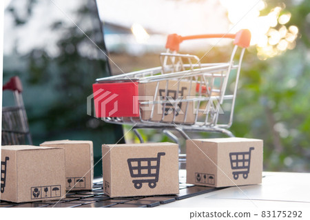 Shopping online - Parcel or Paper cartons with a shopping cart logo in a trolley on a laptop keyboard. Shopping service on The online web. offers home delivery. 83175292