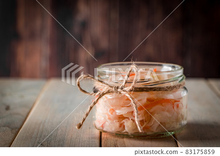 Homemade sauerkraut on a dark brown background. Fermented cabbage in a jar on a wooden background. Eco food, the trend of healthy eating. Place for your text. Homemade sauerkraut on a dark brown background. Fermented cabbage in a jar on a wooden background. Eco food, the trend of healthy eating. Place for your text. 83175859