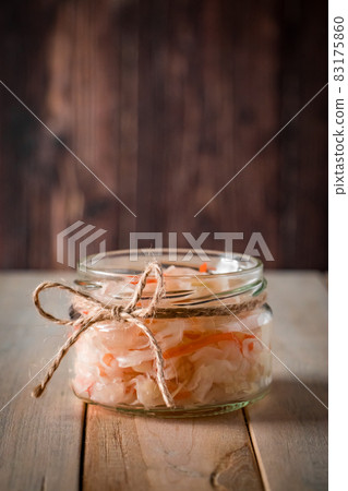 Homemade sauerkraut on a dark brown background. Fermented cabbage in a jar on a wooden background. Eco food, the trend of healthy eating. Vertical photo, place for text Homemade sauerkraut on a dark brown background. Fermented cabbage in a jar on a wooden background. Eco food, the trend of healthy eating. Vertical photo, place for text 83175860